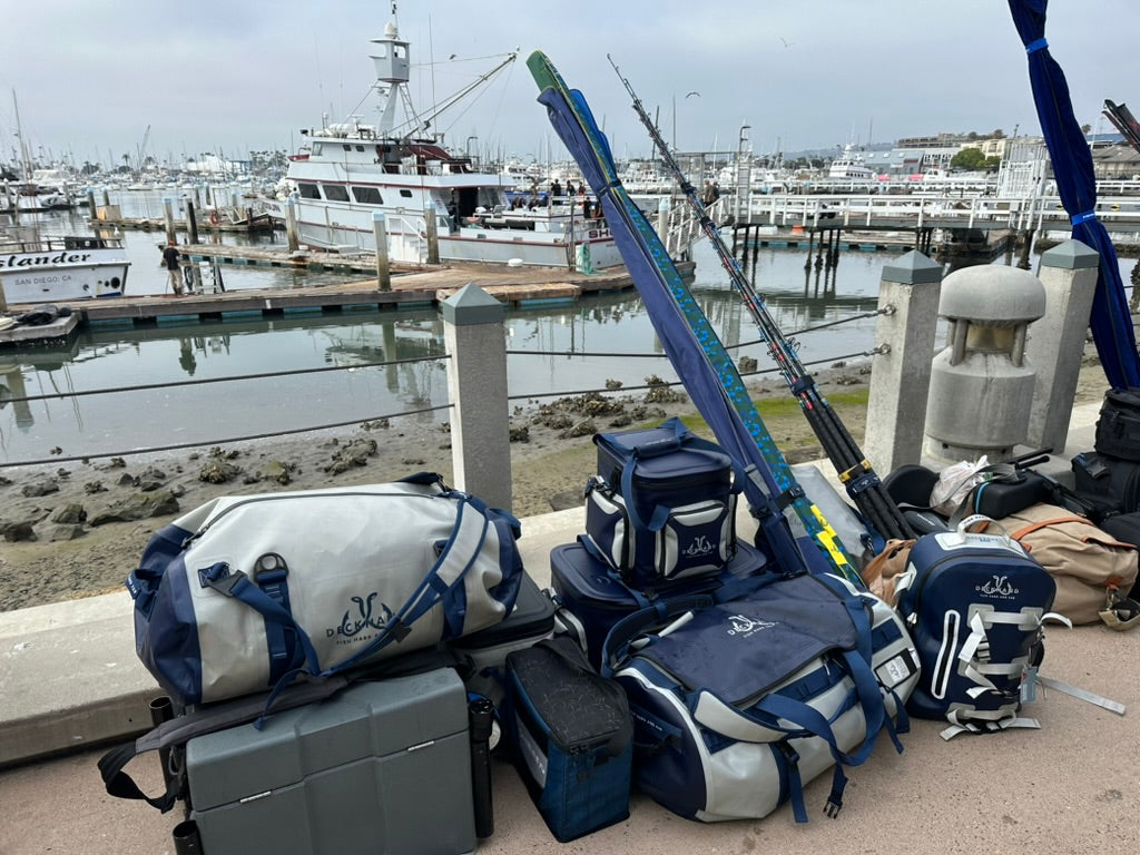 Well-organized fishing tackle storage on a boat deck with various high-quality gear from Deckhand Sports, set against a serene open water backdrop under a clear sky.