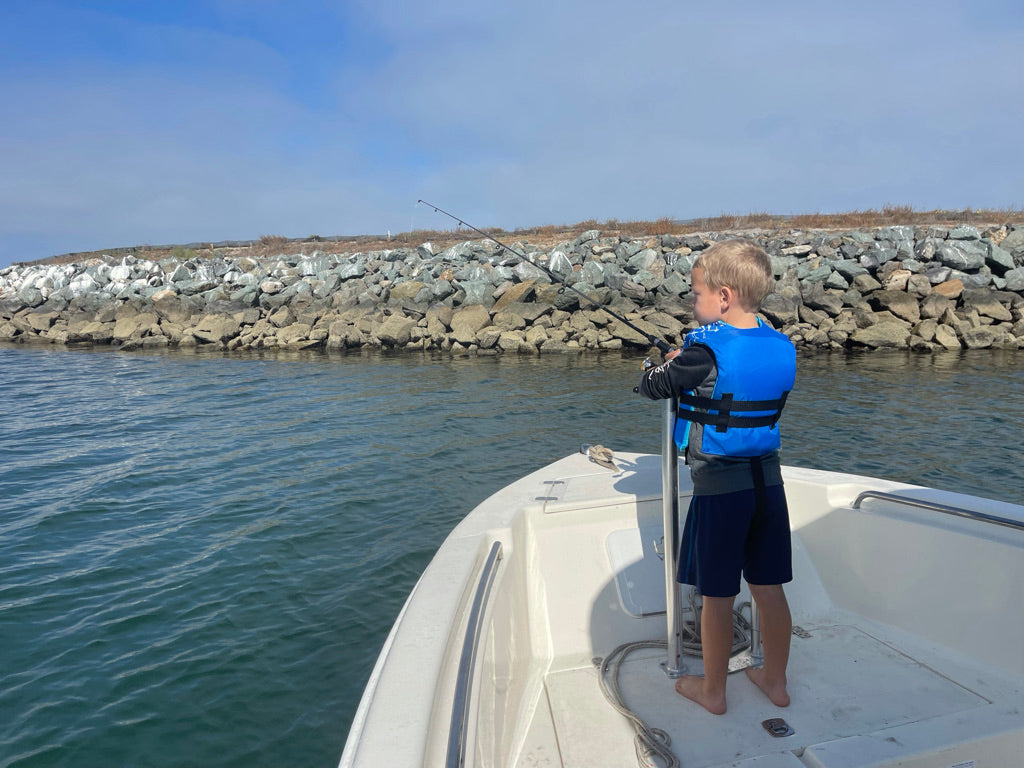 Anglers fishing on boats along the scenic San Diego coastline, showcasing Deckhand Sports gear.